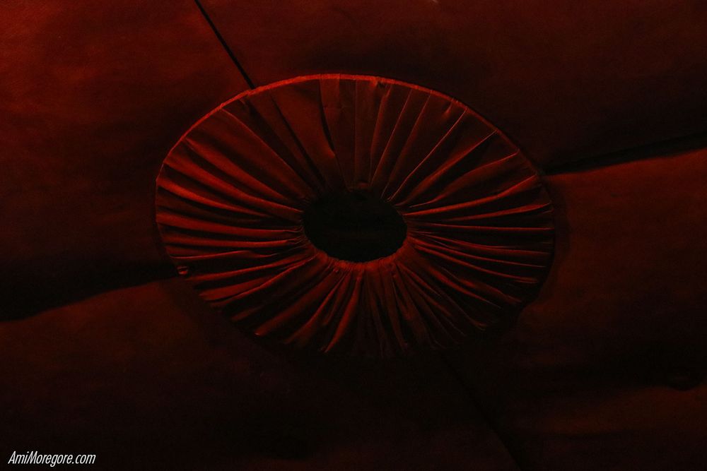 An upholstered ceiling and light fixture sans light that resembles a sphincter