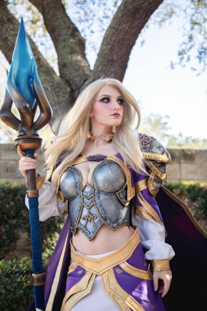 Dark lady dressed as classic jaina Proudmoore from Warcraft and Heartstone, holding her staff and looking off to the right while her cape blows 