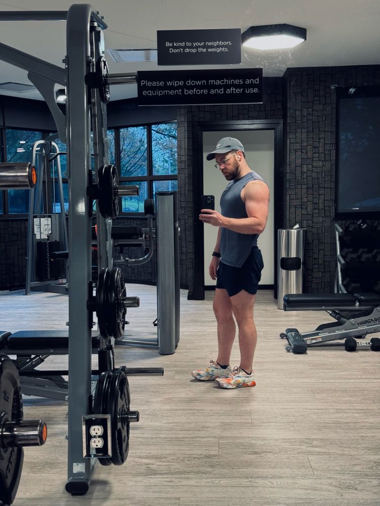 Photo of a gay at the gym wearing a blue outfit, mid-workout, captioning dad jokes.