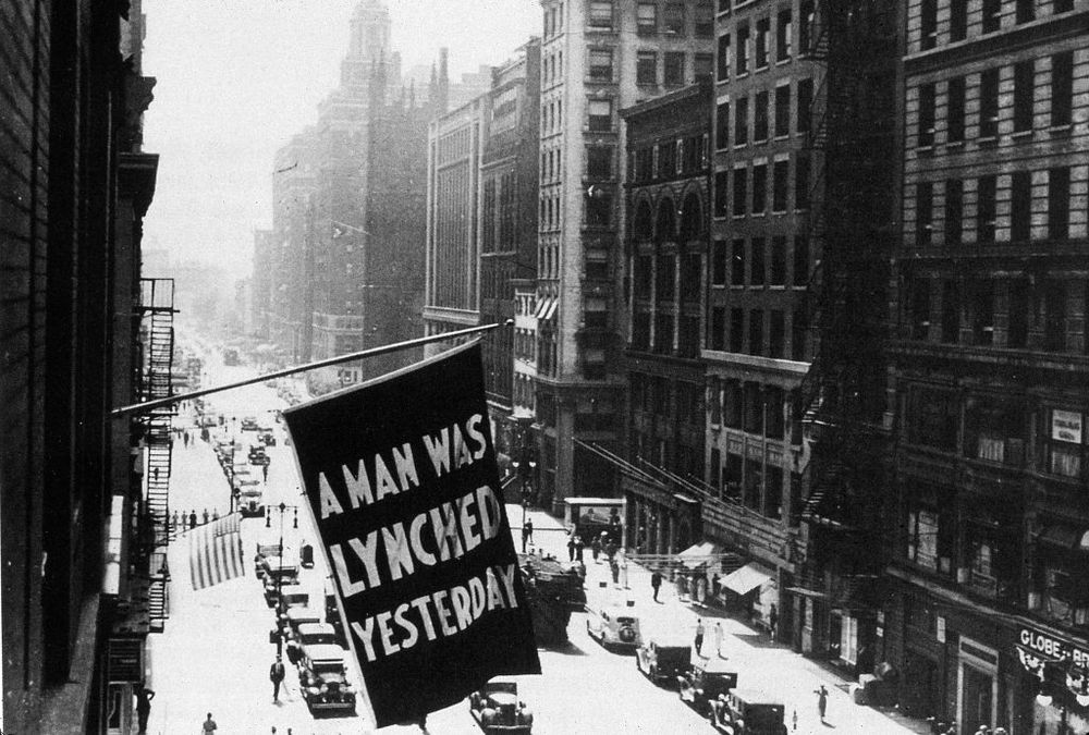 Flag stating "A Man Was Lynched Yesterday" floating over a NYC street in the 1920s