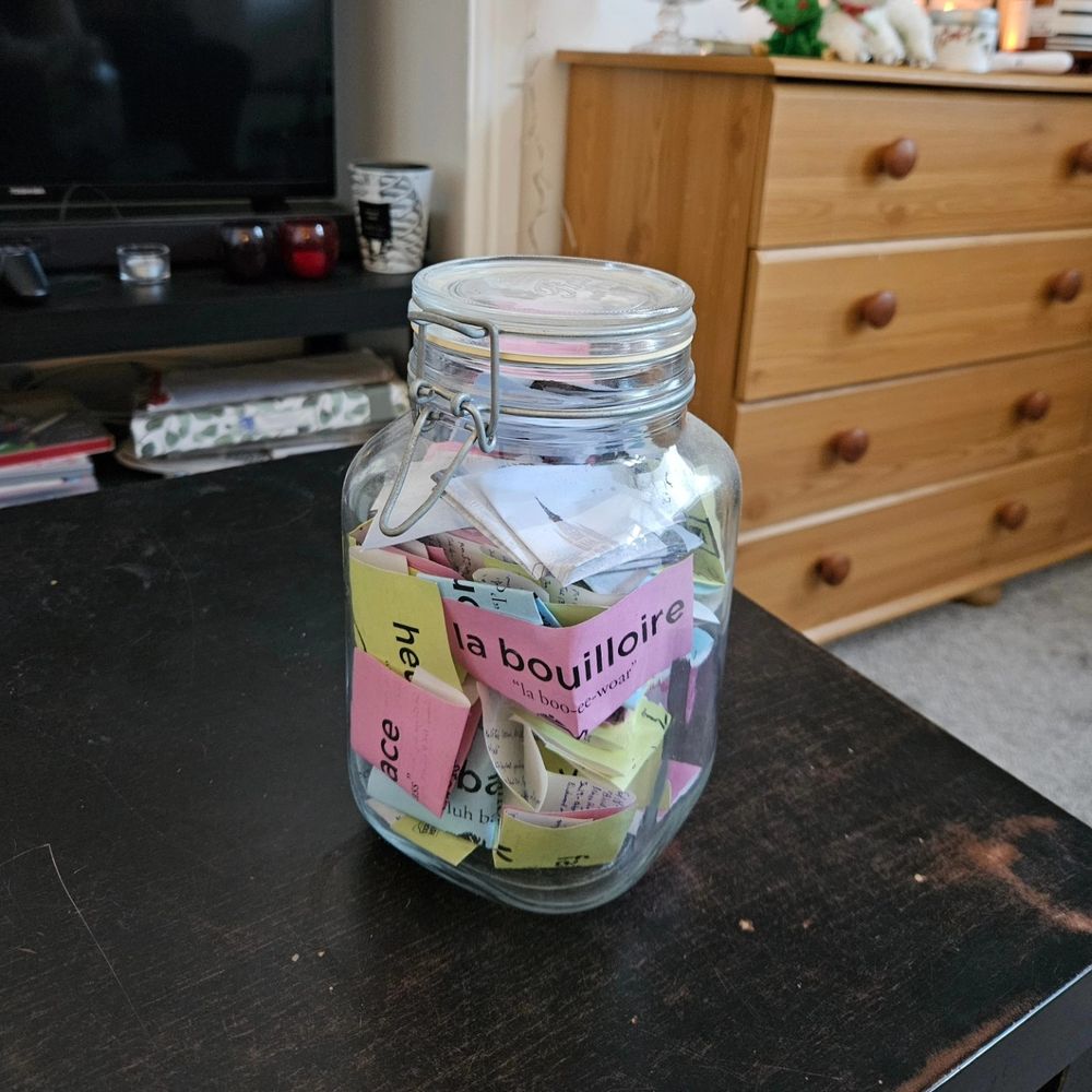 A closed, glass mason jar, with lots of post it notes of different colours (pink, green, blue, etc)
