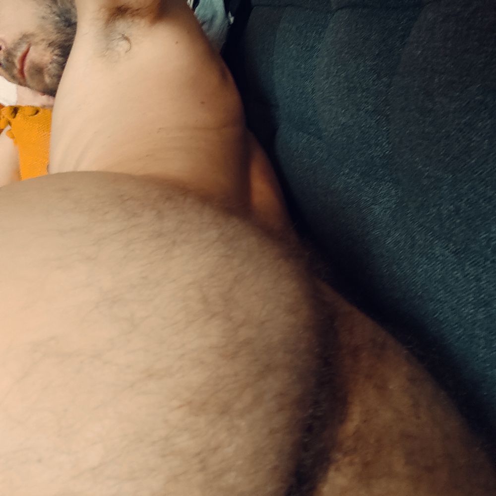 Photo en plan raproché de mon corps nu allongé sur mon canapé, cadré serré sur le haut de mon cul poilu, dans l'angle de fuite où est la mise au point on aperçoit mon aisselle decouverte et le bas de mon visage.