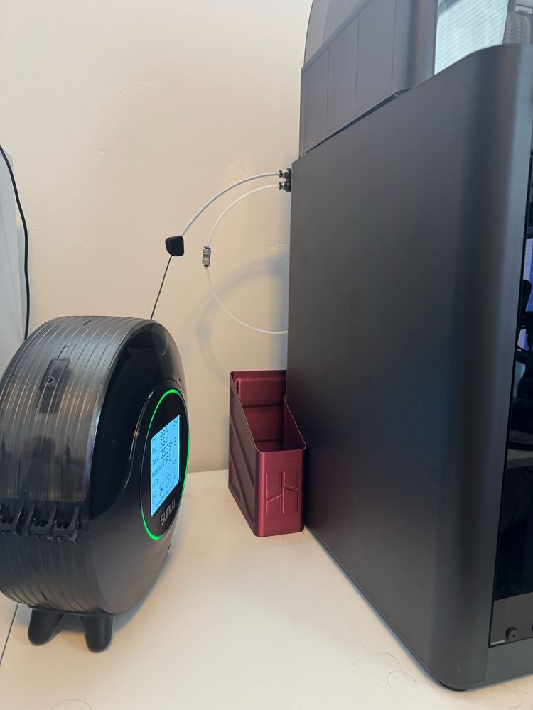 A filament dryer with TPU filament coming out of it and feeding into the 3D printer. 