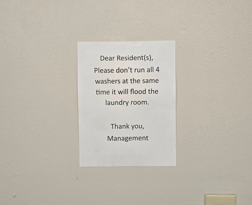Image of sign on wall saying not to run all washers at the same time or else it will flood laundry room