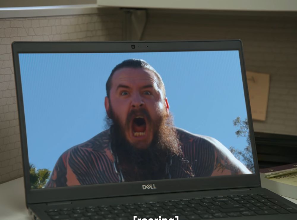 A laptop on a desk with a image of wrestler Brody King shouting from the show I Think You Should Leave