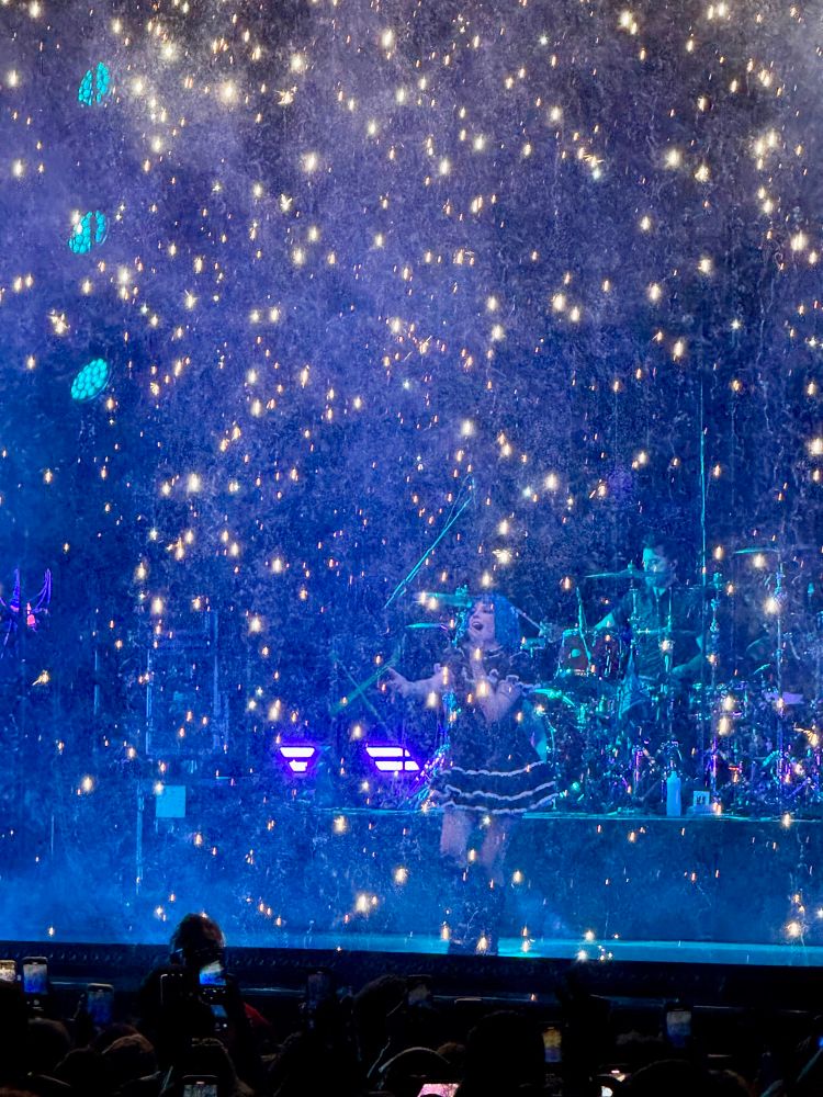 Halsey performing in Camden during song You Should Be Sad, sparklers coming down from top of the stage as she’s singing. Halsey is wearing a blue short hair wig and black babydoll dress with combat boots