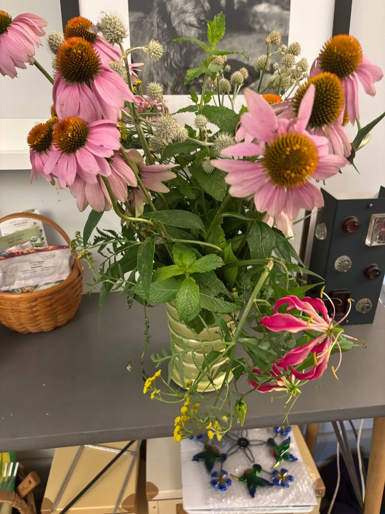 Bouquet of pink and red flowers with pale green little balls and green mint leaves. Bright green ceramic vase. 