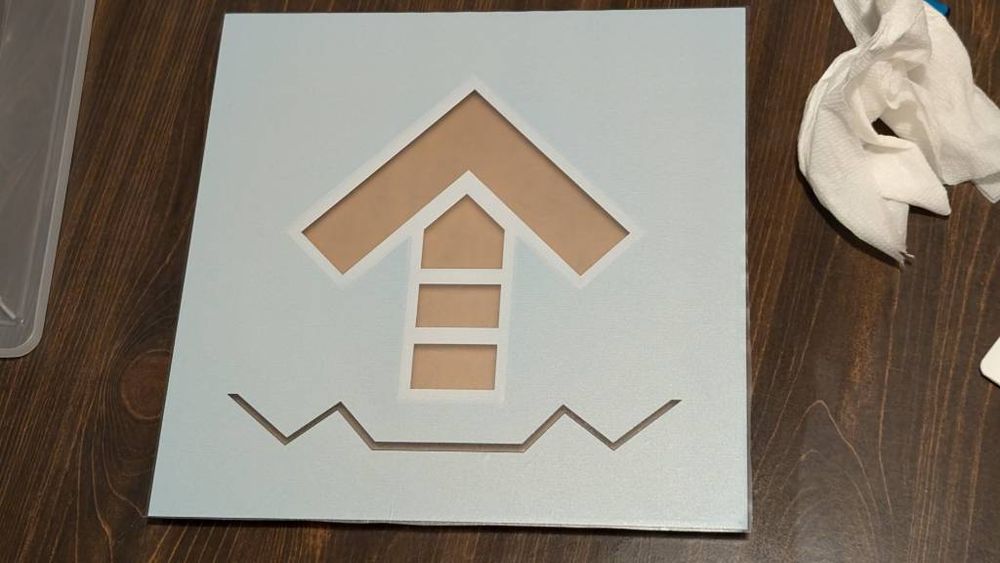 Panel with arrow decal, flipped upside down to reveal that the back is solid white in places where the front is black. The lighting and placement of the panel show that certain sections are semitransparent.