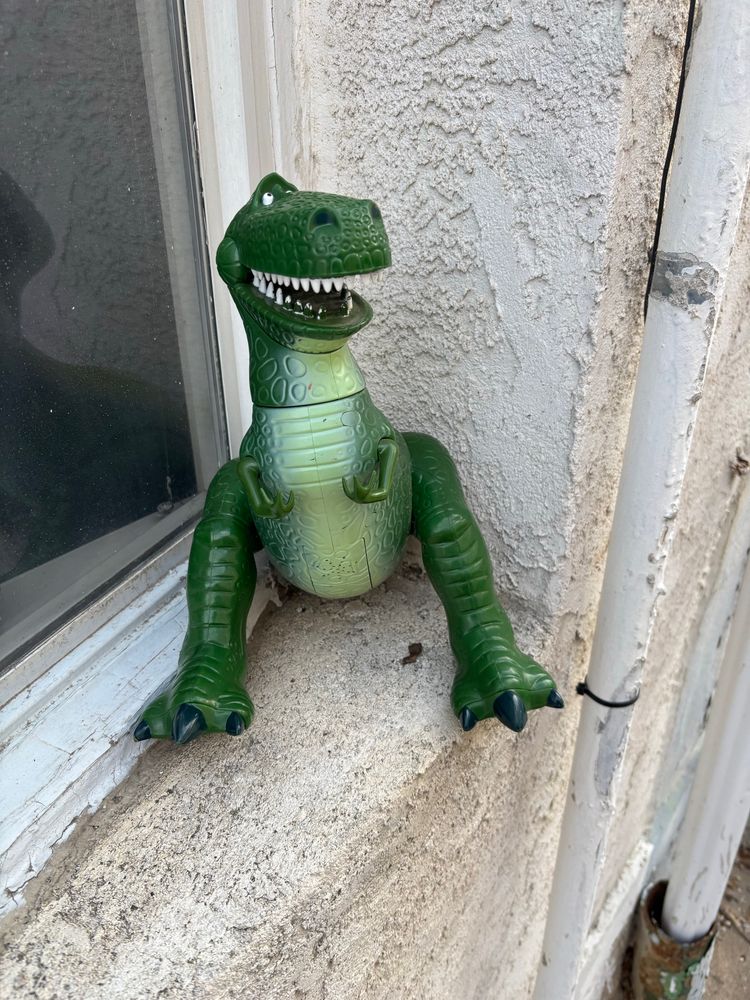 a Toy Story Rex action figure on an outdoor window sill