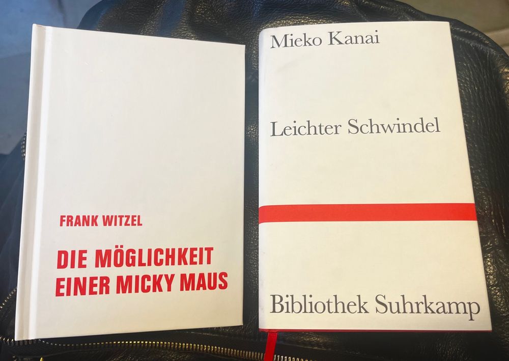 Zwei Bücher, beide weiß. Links rote Schrift auf dem weißen Buch: Frank Witzel Die Möglichkeit einer Micky Maus. Rechts daneben ein weißes Buch aus der Bibliothek Suhrkamp der Autorin Mieko Kanai: “Leichter Schwindel” mit einem roten Balken.