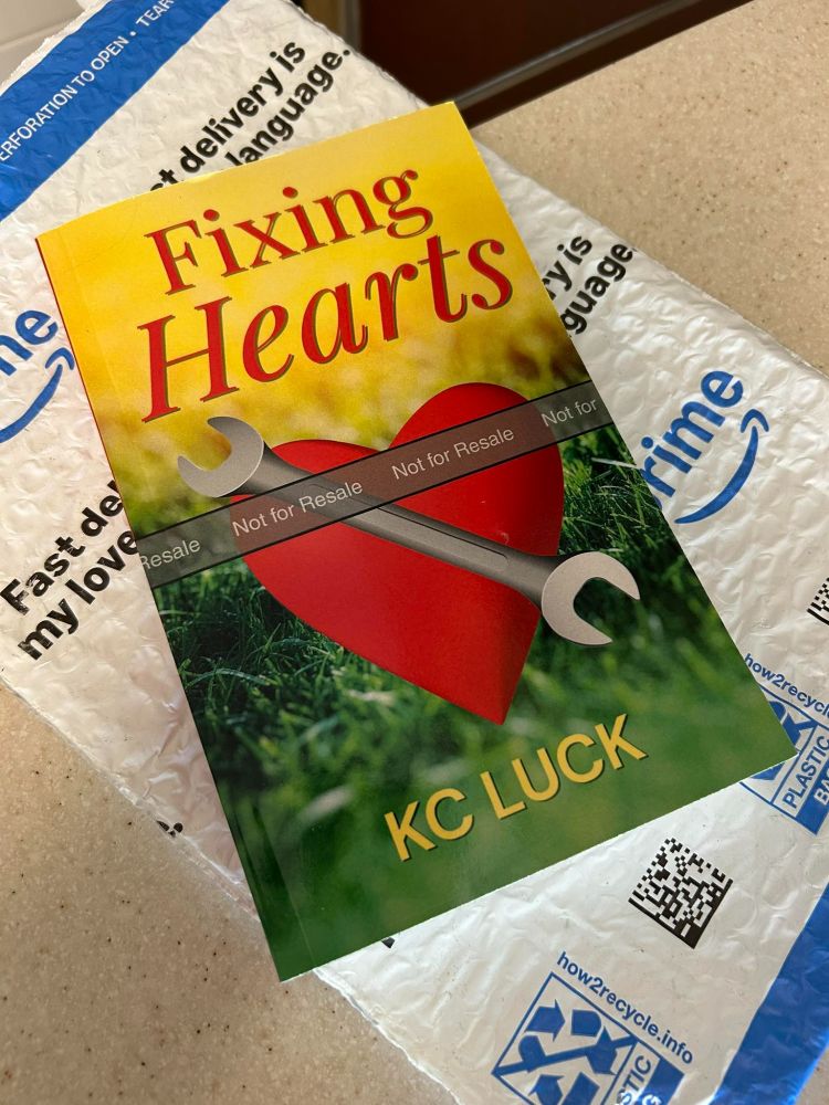 Paperback copy of the novel Fixing Hearts on a blue and white Amazon mailer.