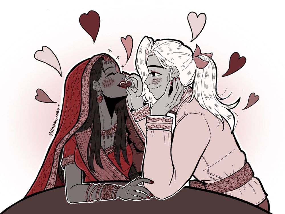 Niran feeds Satya chocolate cake. She is wearing a traditional, Indian bridal outfit, and Niran is wearing a traditional Thai groom outfit. Satya is lightly touching his arm and leaning her head back while she laughs. He is staring directly as her with a smile with his head resting on his hand.