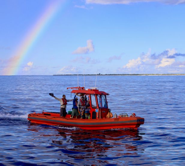 A NOAA small boat returns to ship under a rainbow after collecting water samples and deploying scientific instruments in the Pacific’s Kure Atoll. Credit: James Morioka/NOAA.