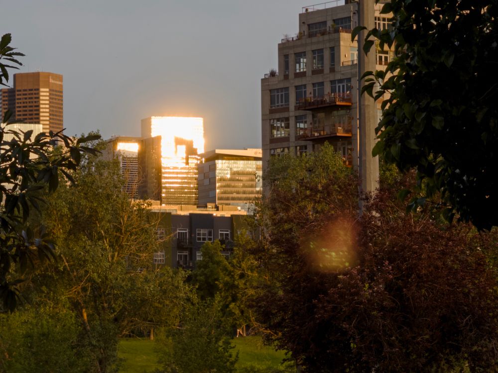 A photo of downtown Denver with the sun reflecting brightly off of a glass building