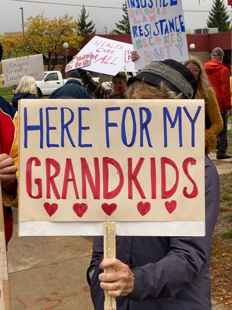 Sign that says “Here for my grandkids” with red hearts