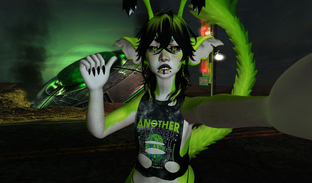 a second life photo of an alien hybrid taking a selfie. he has pale skin with an overlay of neon green fur, large goblin-like ears, big furry antennae, and a furry green tail. his hair is black with green highlights, and he wears a black tie dye shredded crop top. he holds the "camera" with one hand, and with the other is pointing his thumb to the background, in which there is a crashed and smoking UFO that glows green. it appears to be nighttime in the middle of a desert, and he is standing across a road from the ship.