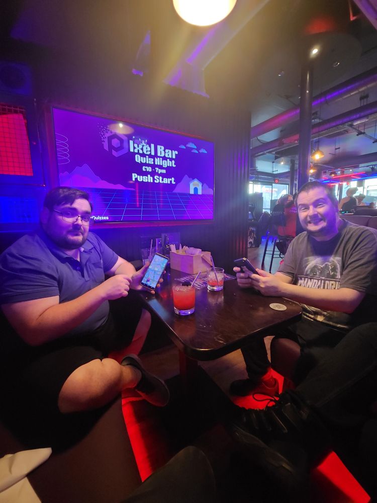 Two friends at the quiz table, playing Pokemon Go