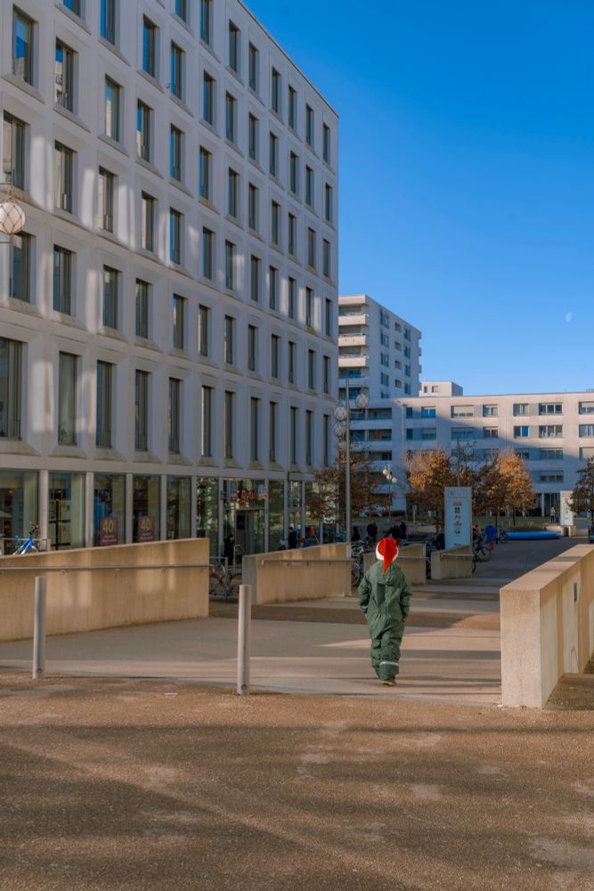Kid with Santa hat in front of buildings 