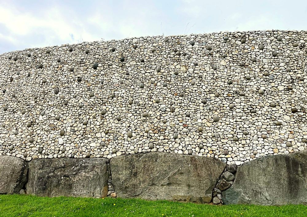 A photograph of the reconstructed quartz outer facade and kerbstones of Newgrange passage tomb.