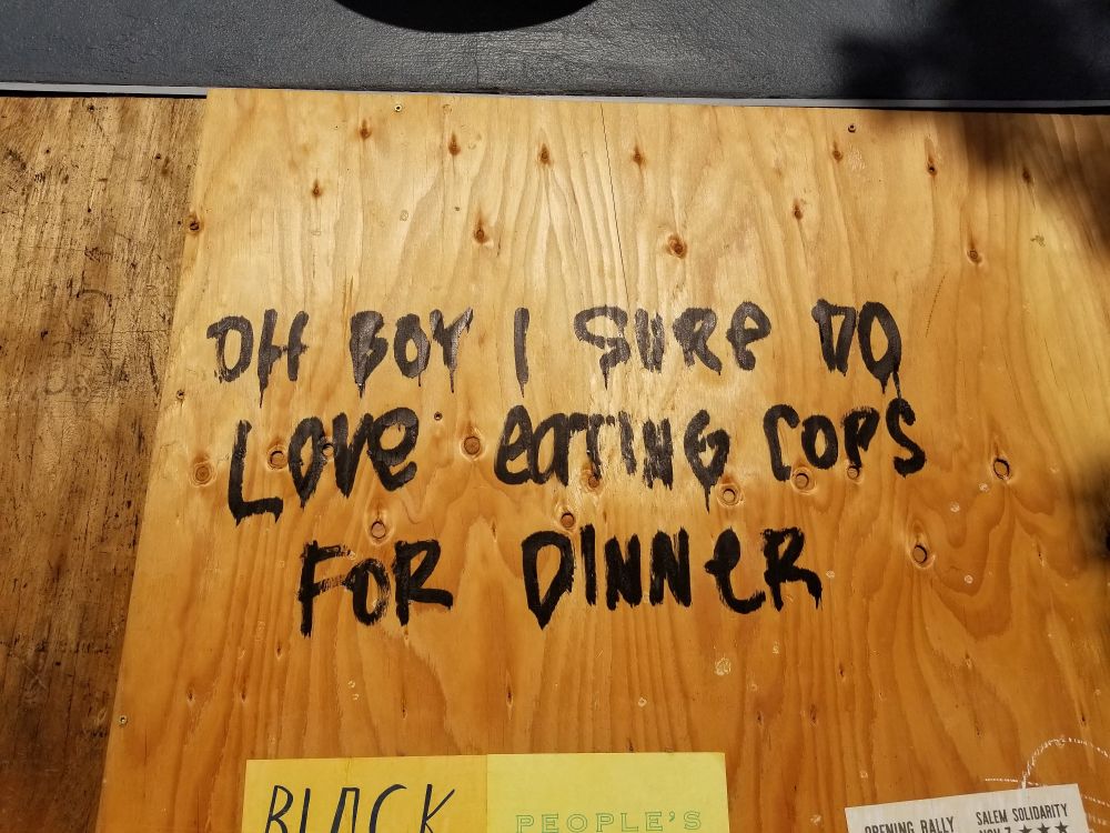 A painted wall that says "Oh boy I sure do love eating cops for dinner."
