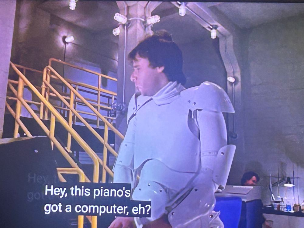 Rick Moranis as Bob McKenzie in STRANGE BREW, fiddling with a synthesizer and saying, “Hey, this piano’s got a computer, eh?”