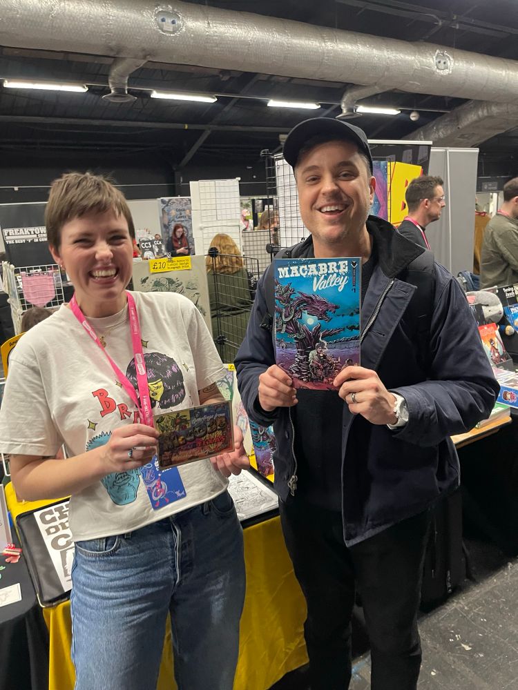 Anna Readman and I hold up copies of our comic Macabre Valley and the post card that came with it 