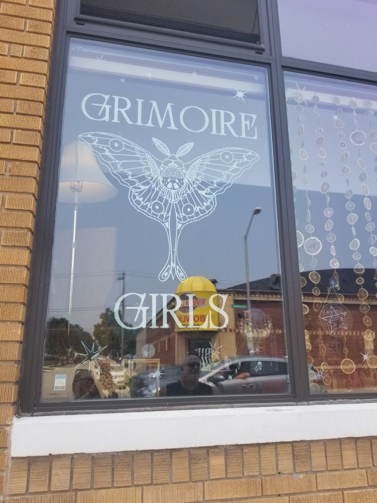 A window sign that reads "Grimoire Girls".