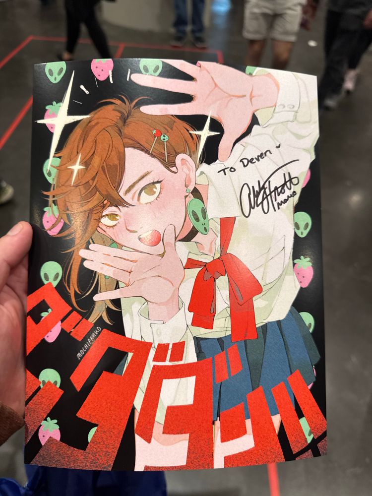 A picture of Momo Ayase doing a cool pose in front of a bunch of aliens and strawberries signed by Momo herself, Abby Trott! SO COOL