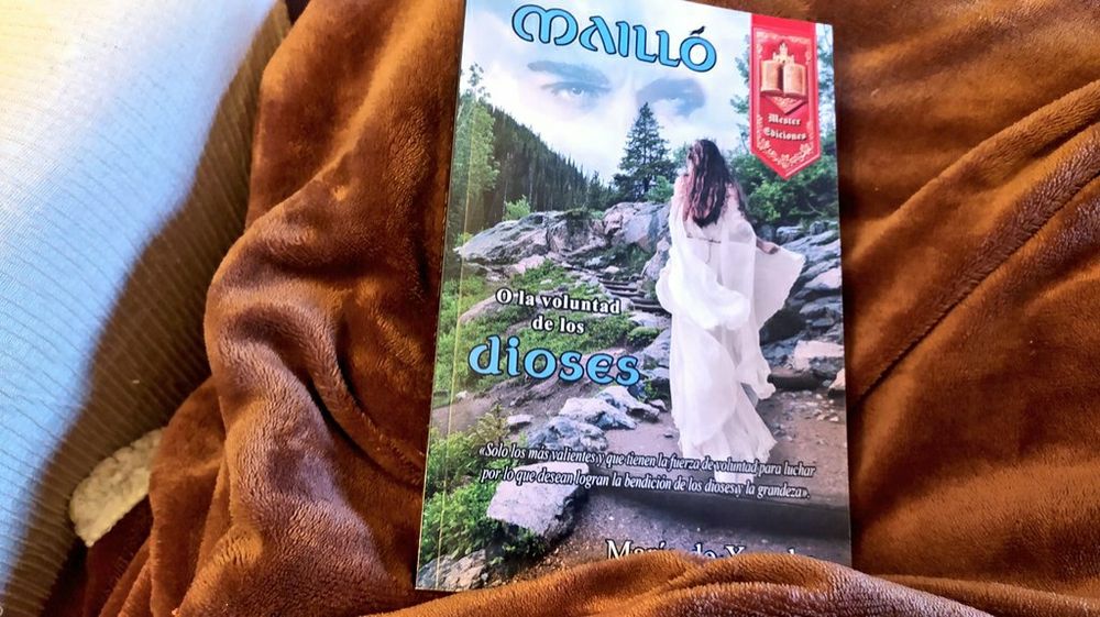 El libro de María sobre una manta marrón calentita que descansa en el sofá de color crema. Un plan perfecto para una tarde de otoño.