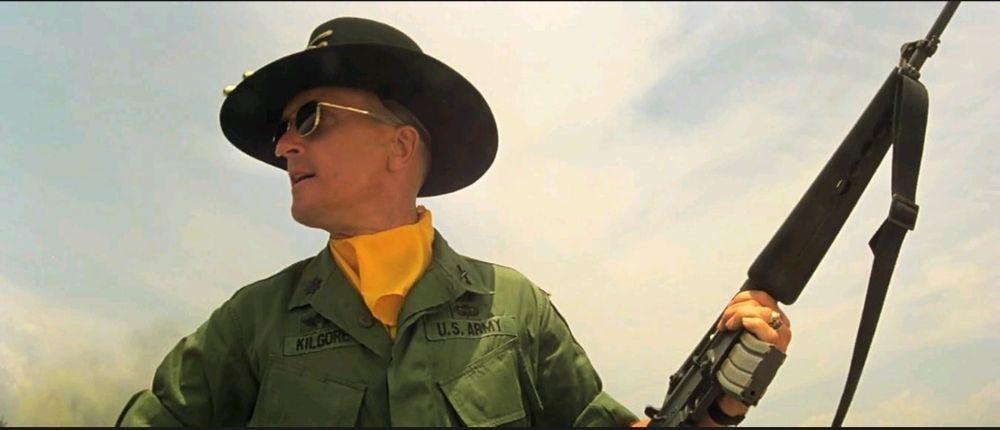 Apocalypse Now: Up shot as Duvall standing profile, military outfit, rifle pointed skyward.