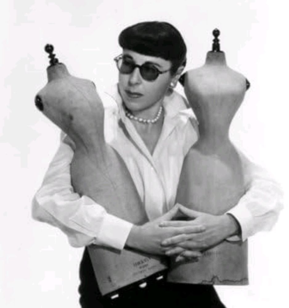 Edith Head holding two dress forms.