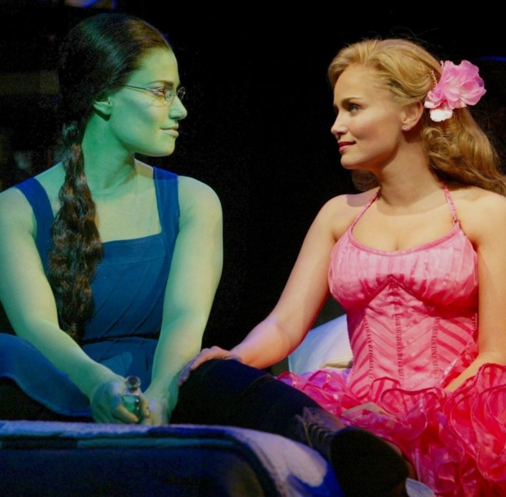 Idina Menzel in green makeup & Kristin Chenoweth in pink dress.