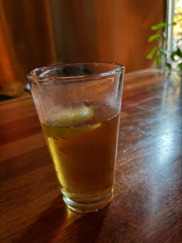 a beer in a frosty glass with a lime floating in it 