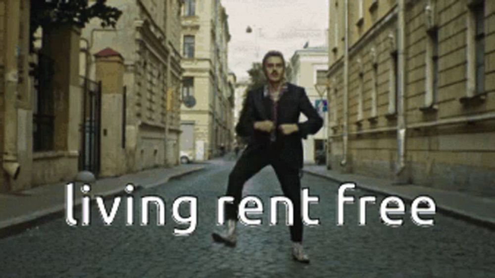 a man in a suit is dancing on a cobblestone street with the words living rent free above him