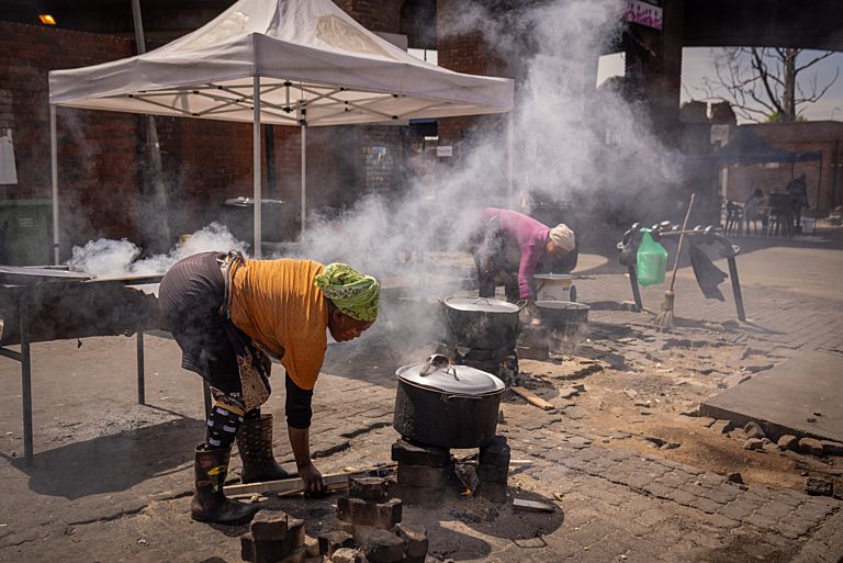 People cook on open fires outside the Kwa Mai-Mai Market in Johannesburg, South Africa, on November 22, 2023. Credit: Gulshan Khan/Climate Visuals