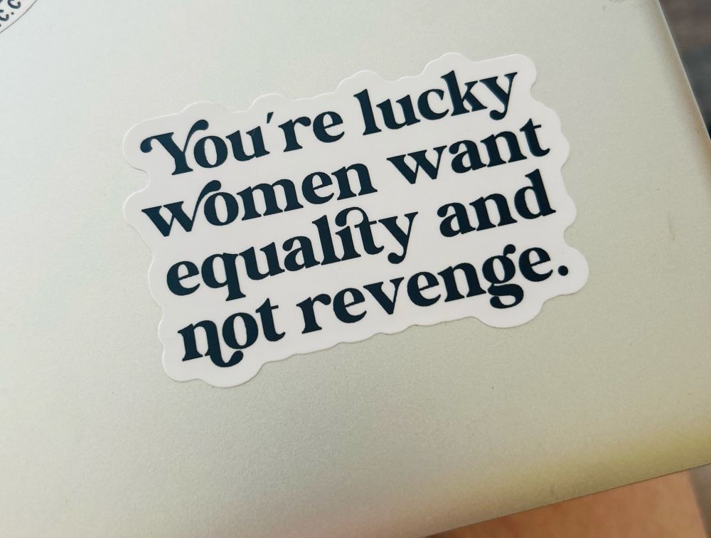 A vinyl sticker with a white background and it says with black font, you’re lucky women want equality and not revenge