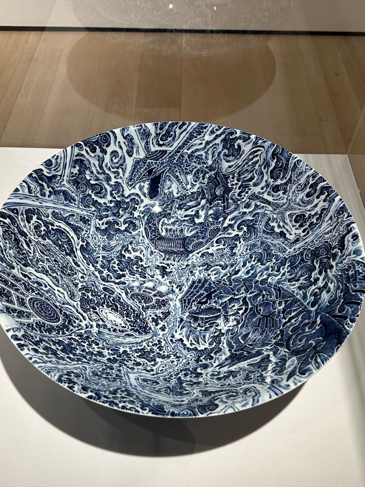 A huge porcelain bowl with blue ink on white depicting the three legendary Pokémon of Hoen (Rayquaza, Kyogre, and Groudon). Lightning bolts, crashing waves, flames, and steam fill the Pokémon’s shapes and the surrounding space.