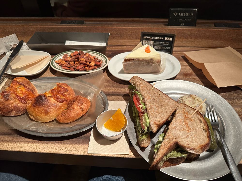 Glazed and roasted nuts, carrot cake, cheese bread, curry pan, fruit cup, and a big B.L.A.T. sandwich with a pickle and potato salad on the side.