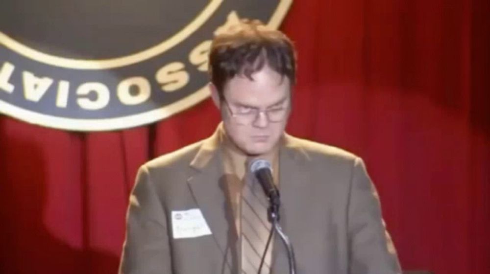 a man in a suit and tie is giving a speech in front of a sign that says social