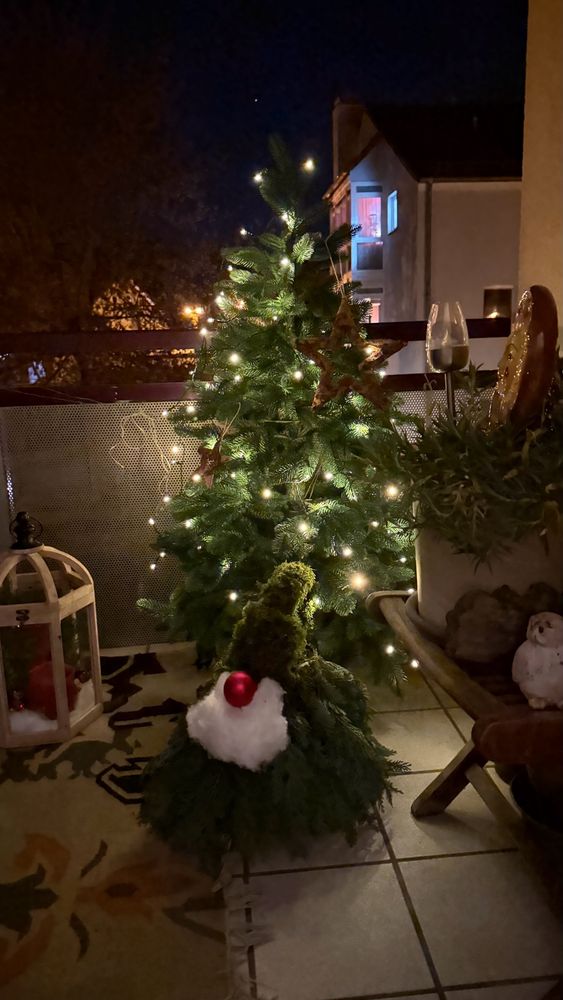 Christmas tree with electric candles and a self-made gnome in front of it - all photographed in the dark
