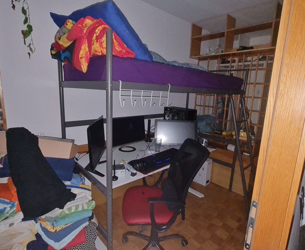 huge desk with a 3 monitor pc set up nestled u der a loft bed