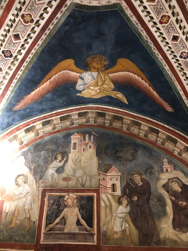 An Angel with the head of a brown cow at the top of an arch above scenes of Jesus and saints.