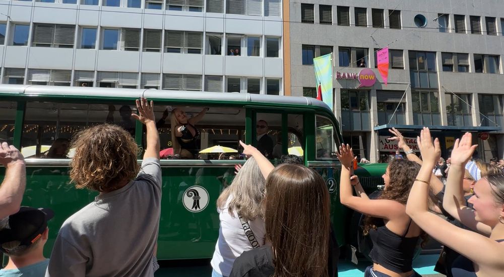 Millie pointing to a tram with Erika Vikman stood inside, she points back through the window