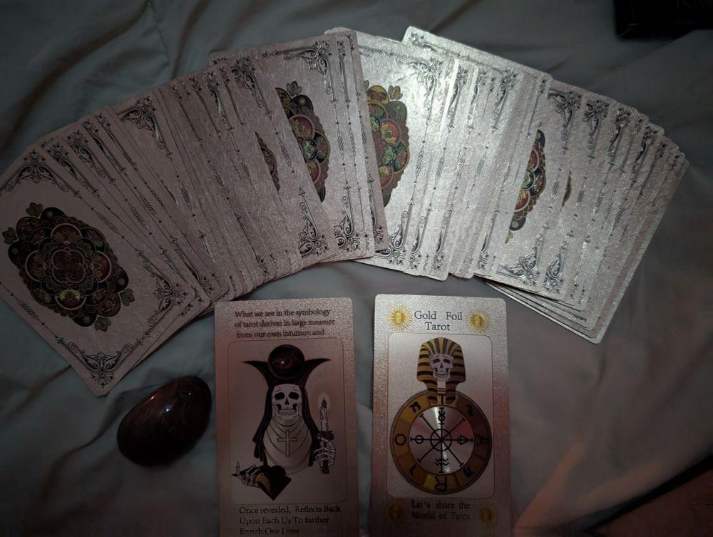 A classic Rider Waite tarot deck. Gold foil printed with raised lettering. 

Colorful Mandalas emblazoned on the back of the cards. 

A rutilated quartz palm stone sitting next to the spread out deck. 
