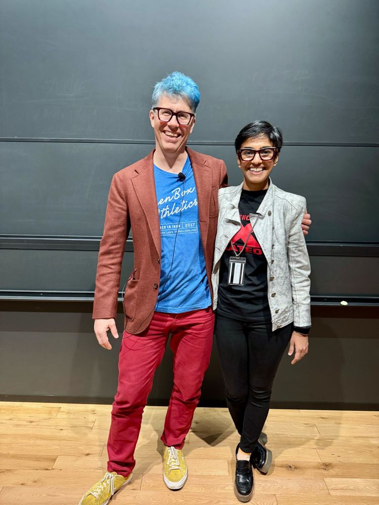 Kanaka and Konrad smiling together in front of a blackboard
