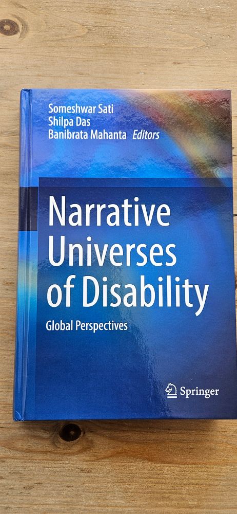 The image shows a blue book with the title Narrative Universes of Disability: Global Perspectives, edited by Someshwar Sati, Shilpa Das and Banibrata Mahanta. The publisher is Springer.