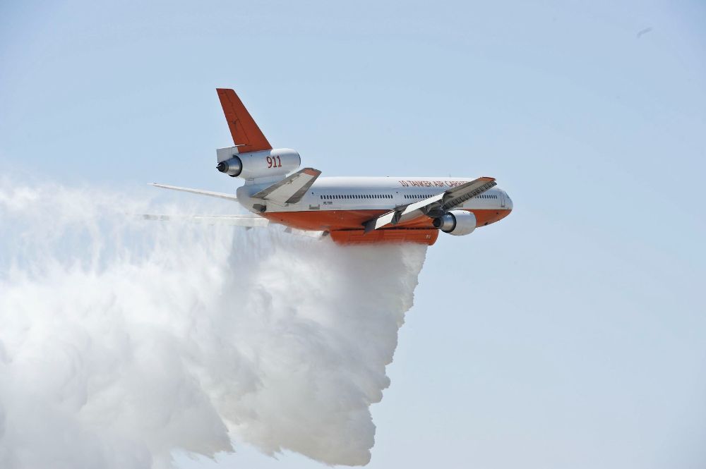 Photo of a MD-11/DC-10 aircraft dropping water as a fire fighting water bomber.