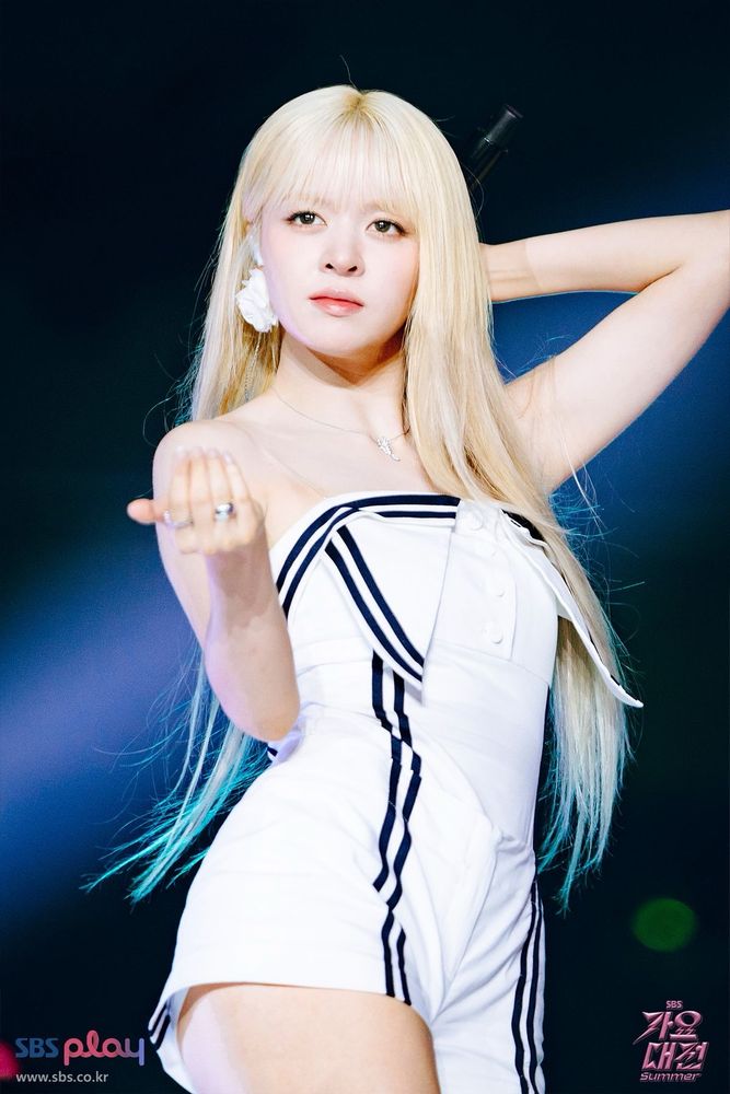 Photo of lily from kpop group nmixx wearing a deconstructed white sailor performance outfit with long blonde hair onstage mid  dancing 