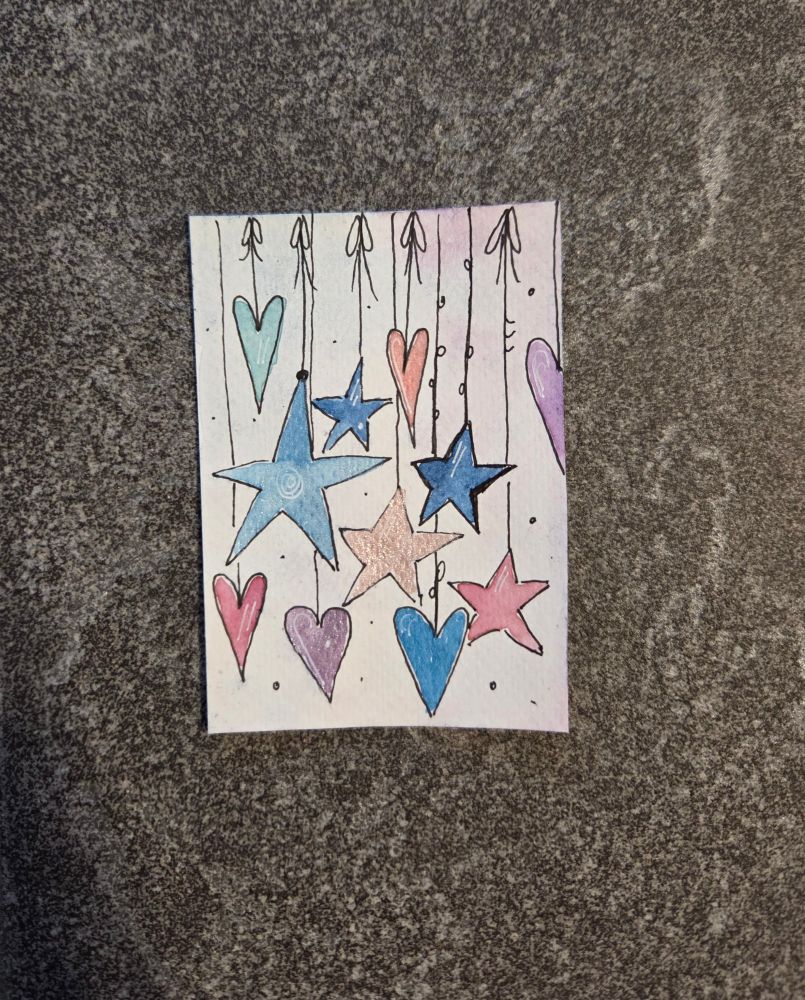 ATC Karte mit bunten Sternen und Herzen, die an Fäden hängend von oben nach unten hängen.