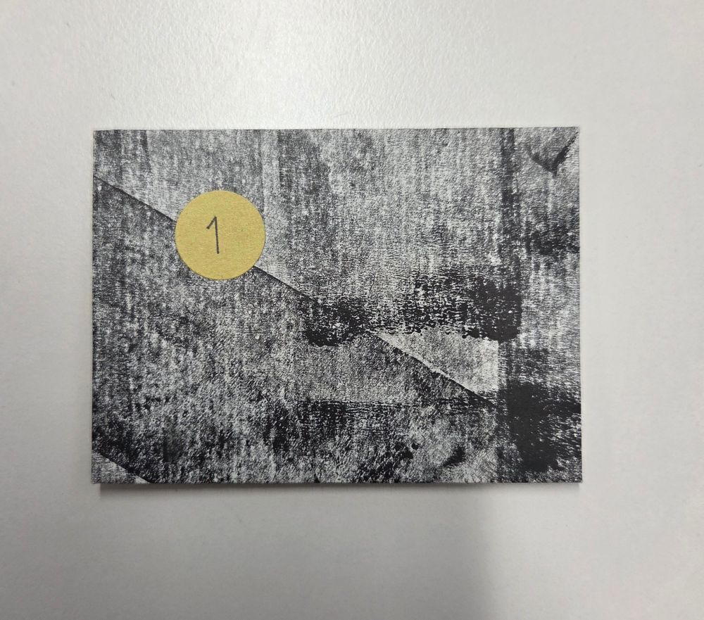 In grauem Packpapier verpackte ATC mit der Nr. 1 auf einem runden, goldenen Kleber oben links